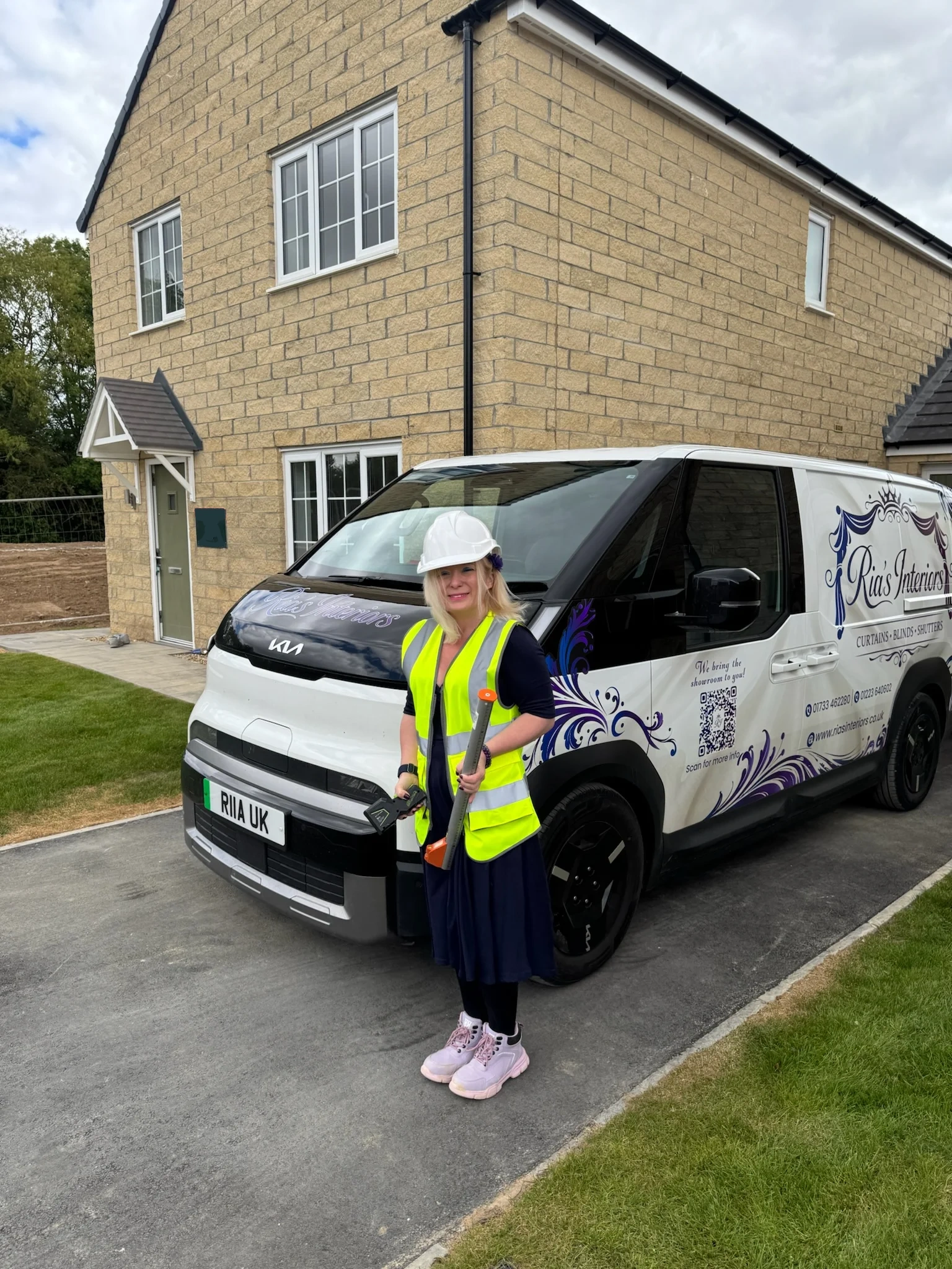 Ria from Ria's Interiors holding samples beside the branded electric van