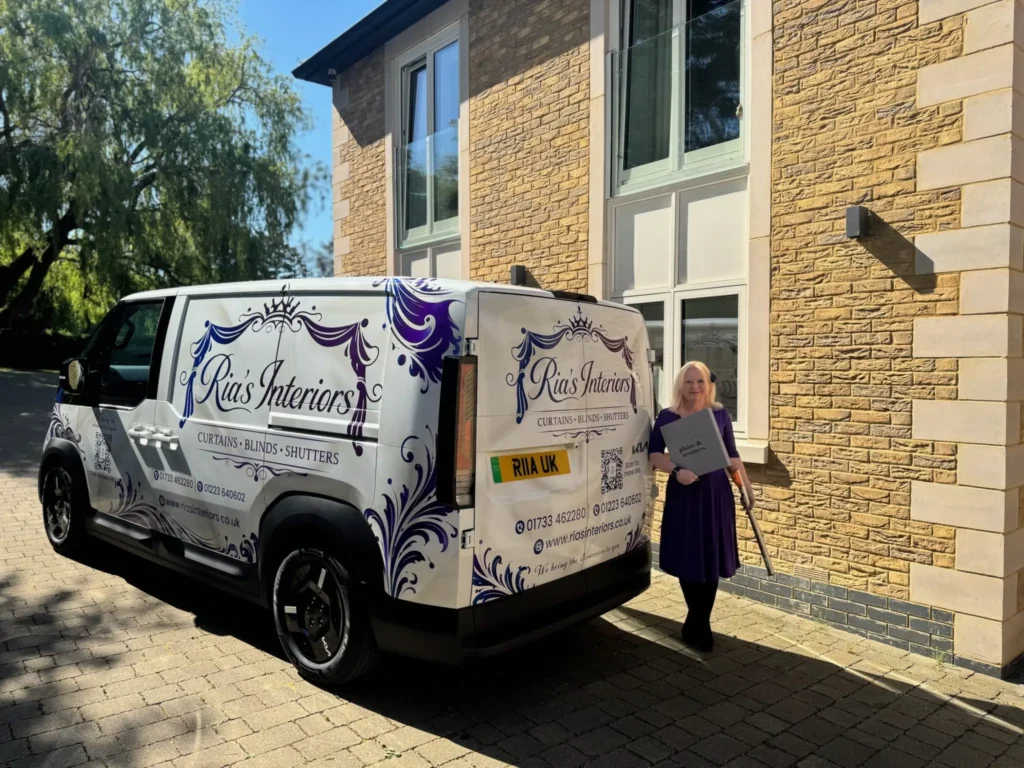 Ria with Luther Van outside a customer's stone-built home, arriving with curtain fabric books