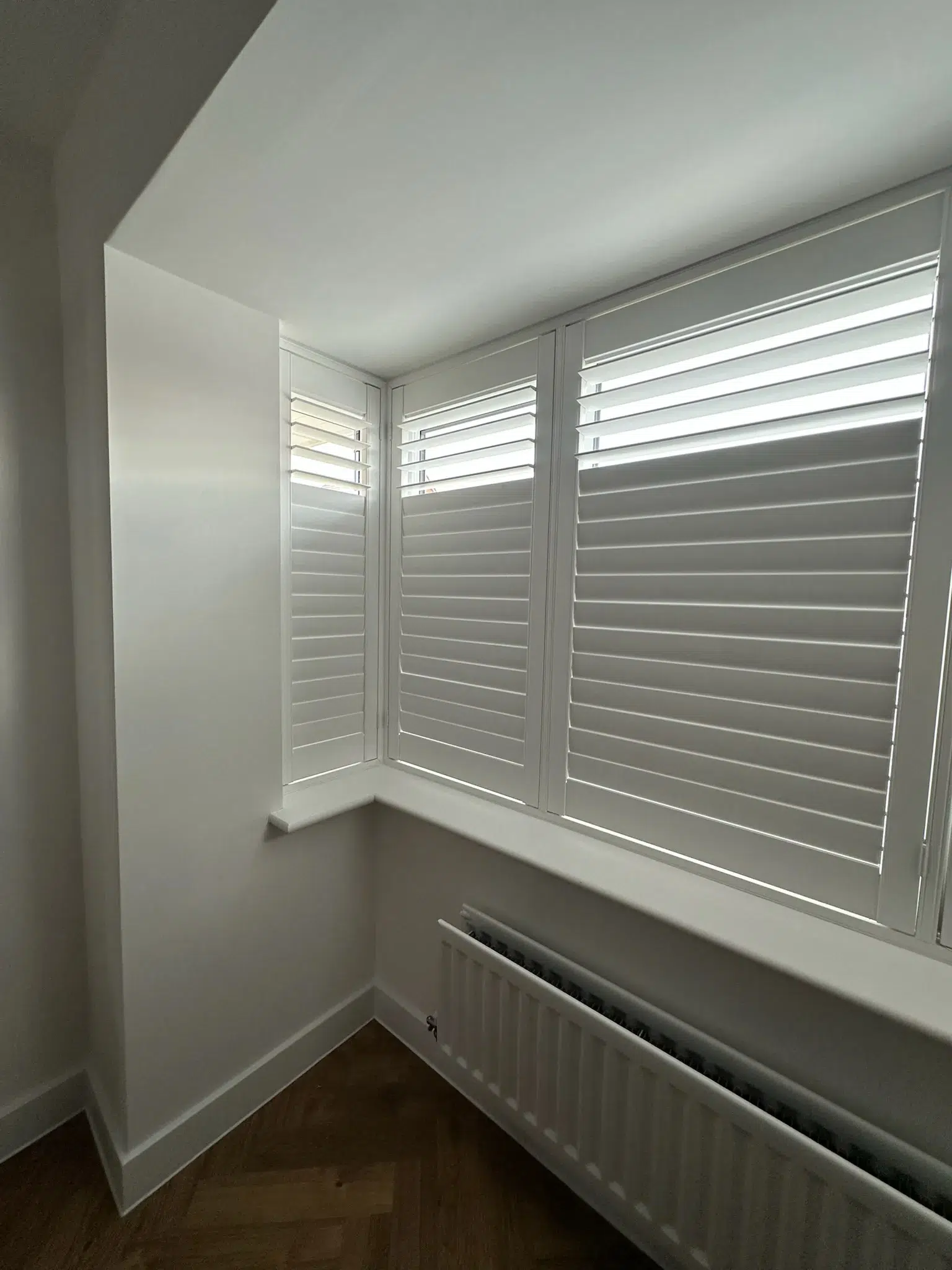 White shutters fitted around a corner window arrangement