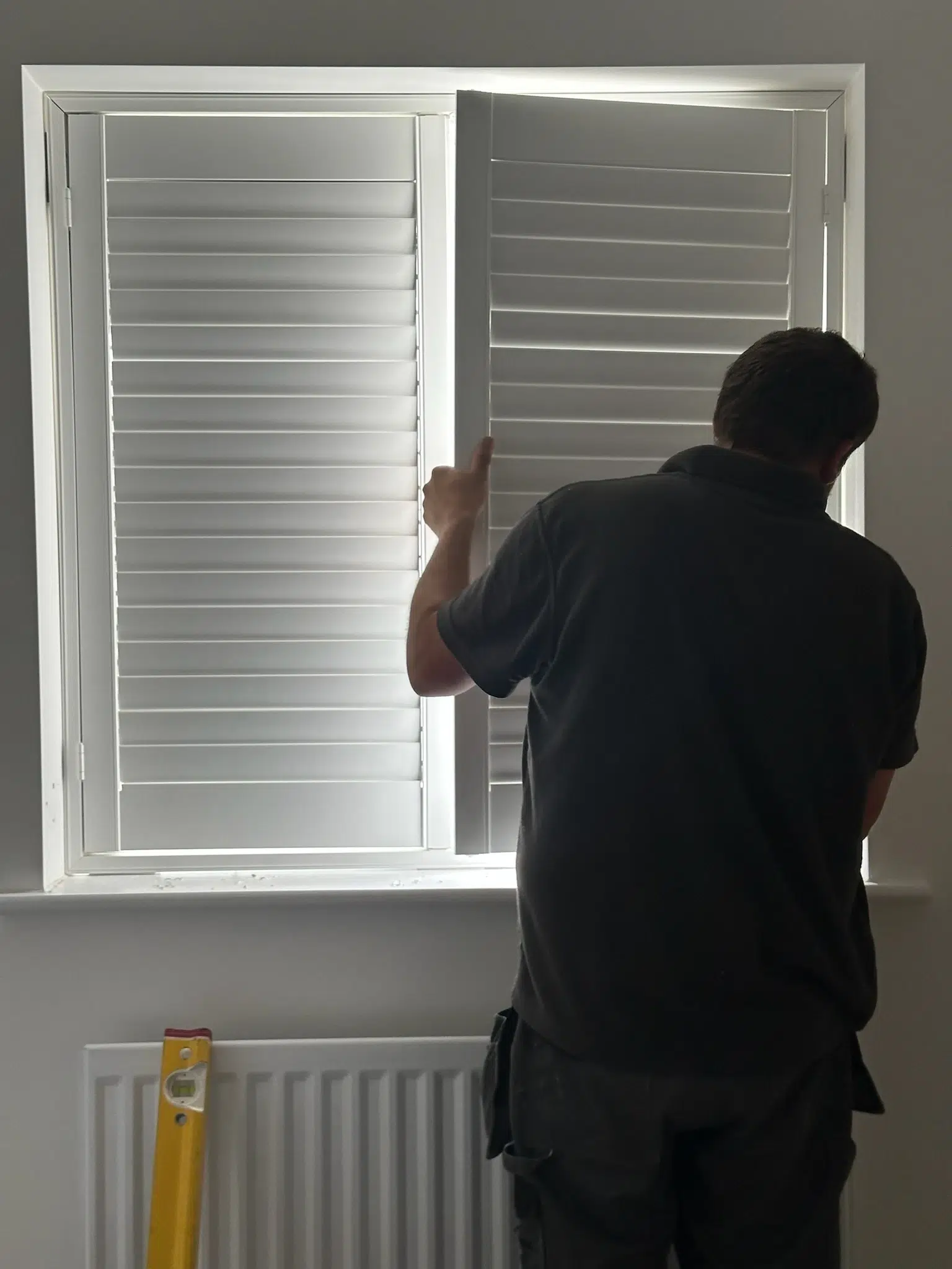 A fitter adjusting a shutter panel during installation
