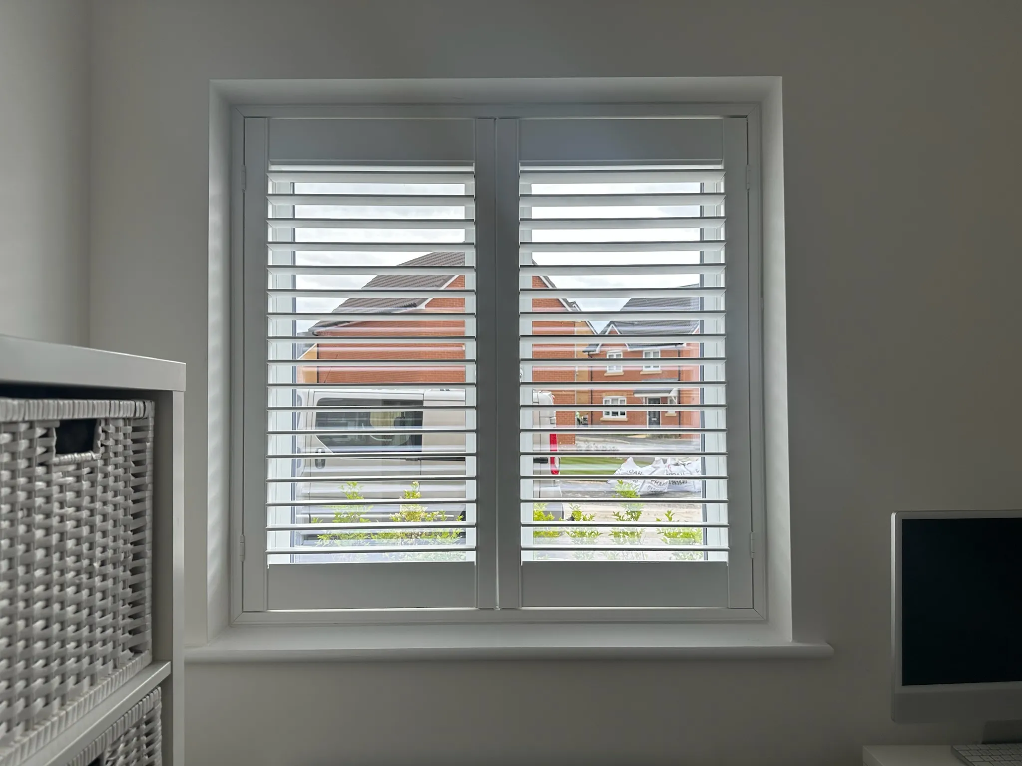 White shutters with louvres angled open on a square window