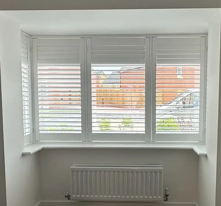 White made-to-measure shutters fitted across a three-section bay window