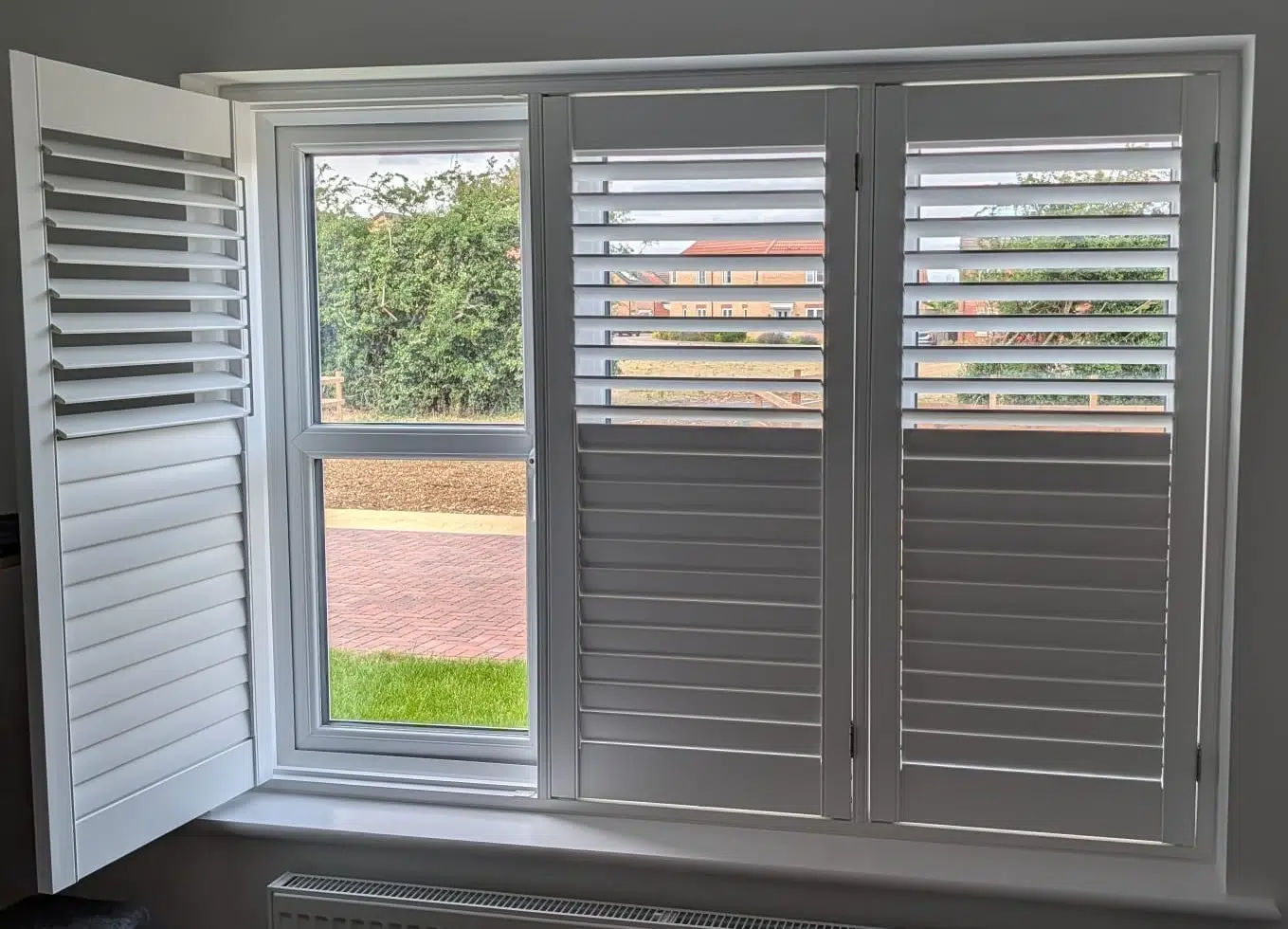 White shutters on a wide window, with one panel swung open