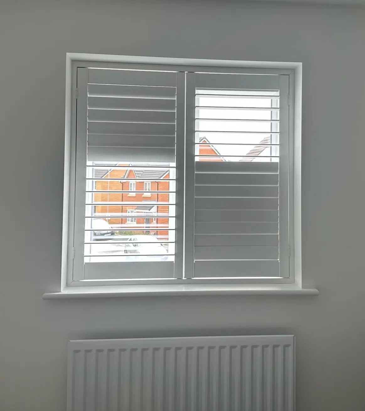 White shutters fitted to a bedroom window with the louvres partly open