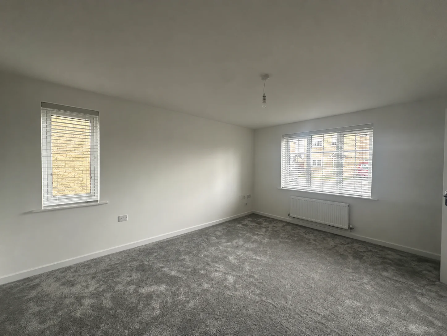 White Venetian blinds fitted at two windows in an unfurnished new-build room
