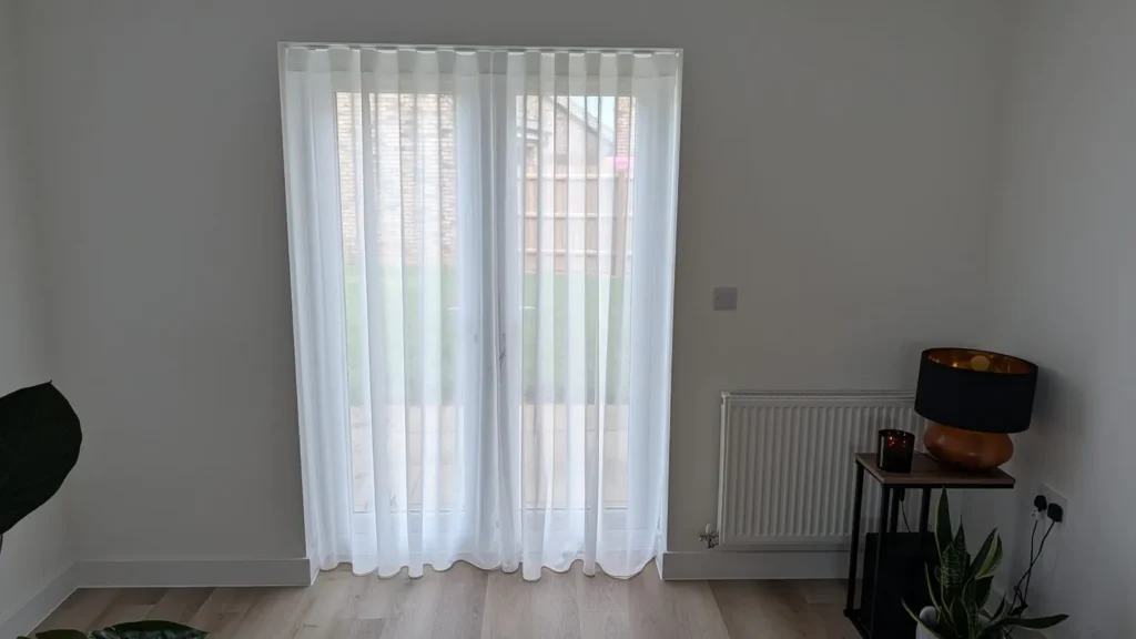 Wave-heading sheer curtains fitted across French doors in a lounge
