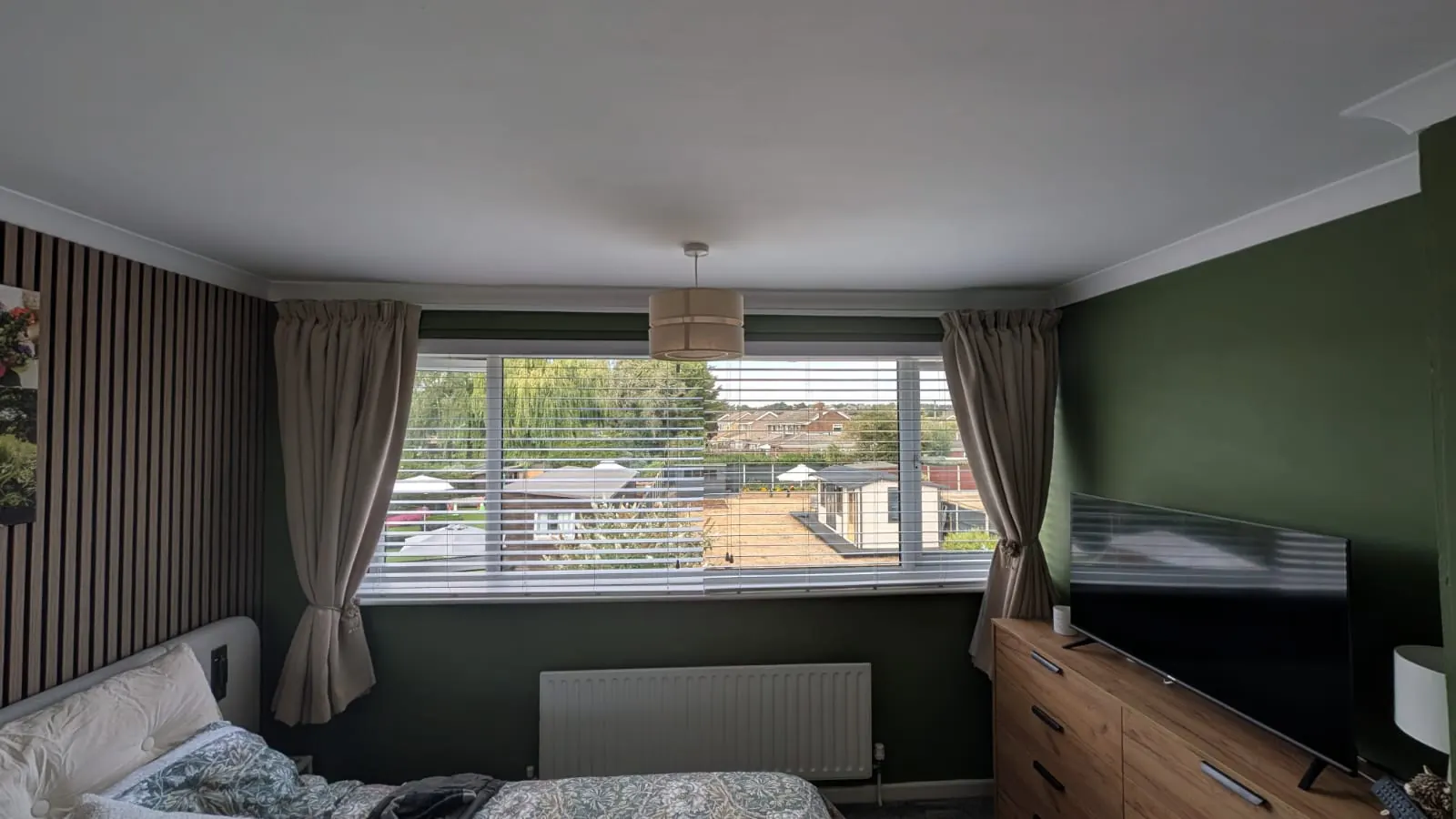 A bedroom with made-to-measure curtains and white venetian blinds across a wide window