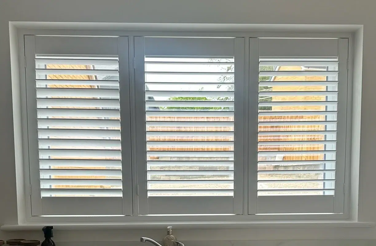 UK-made white shutters fitted in a kitchen by Ria’s Interiors