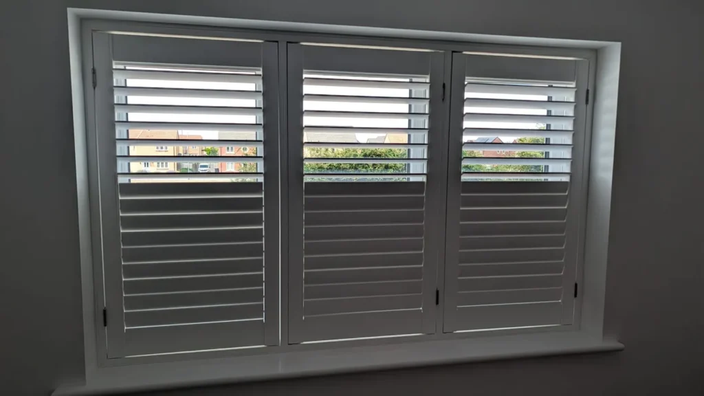 The same white UK-made shutters with the lower louvres shut for privacy and the upper louvres open