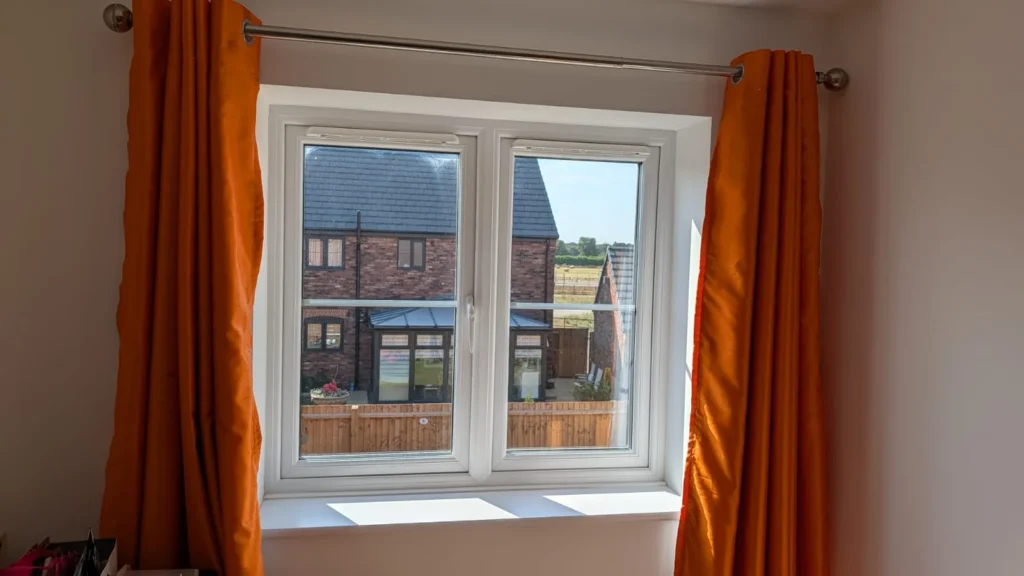 Burnt orange made-to-measure curtains on a pole either side of a bedroom window