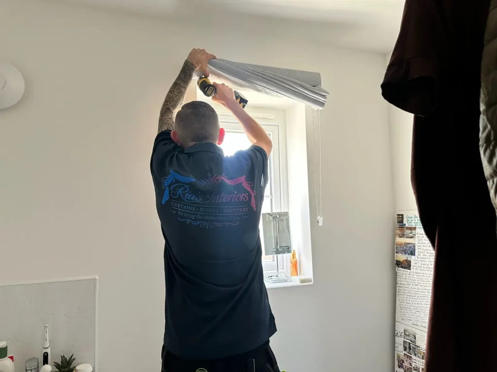 Ria's Interiors fitter installing a Roman blind at a bathroom window