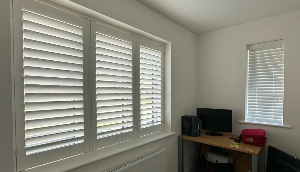 UK-made white shutters beside a wooden Venetian blind in a home office