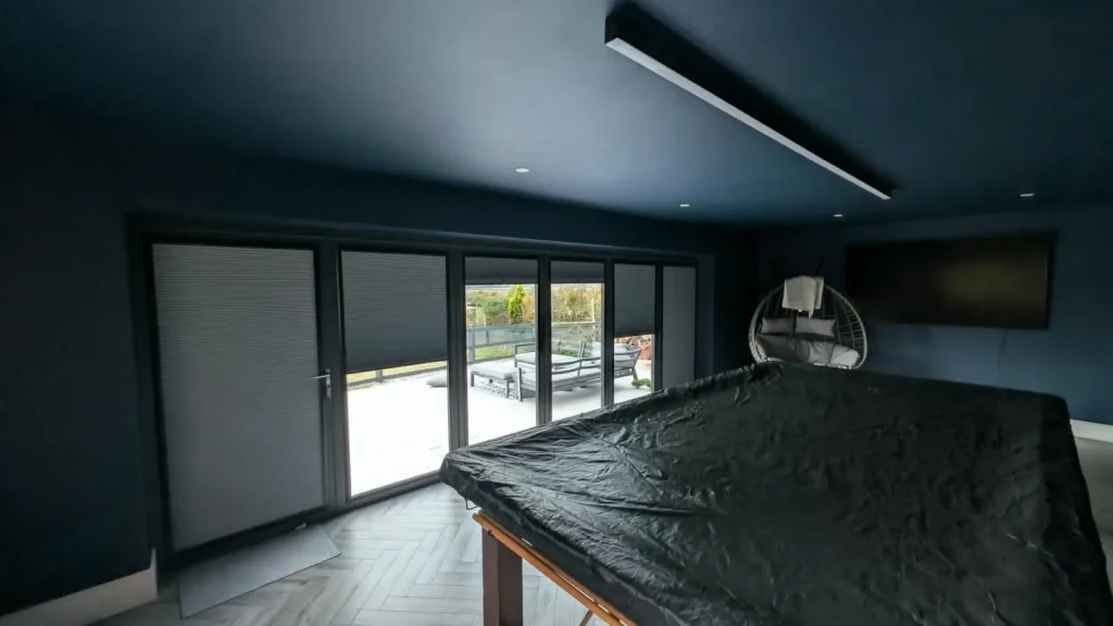 Anthracite Perfect Fit pleated blinds fitted to the glass panels of bifold doors in a games room