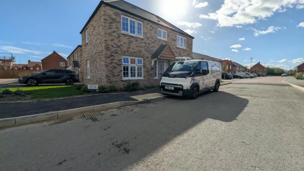 Ria’s Interiors branded mobile showroom van parked outside a new build home, with a Ria’s Interiors sign in the front garden
